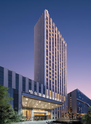 A high-rise hotel with a prominent entrance and a large, illuminated sign. - Steigenberger Harbin Sunac Land (Harbin)