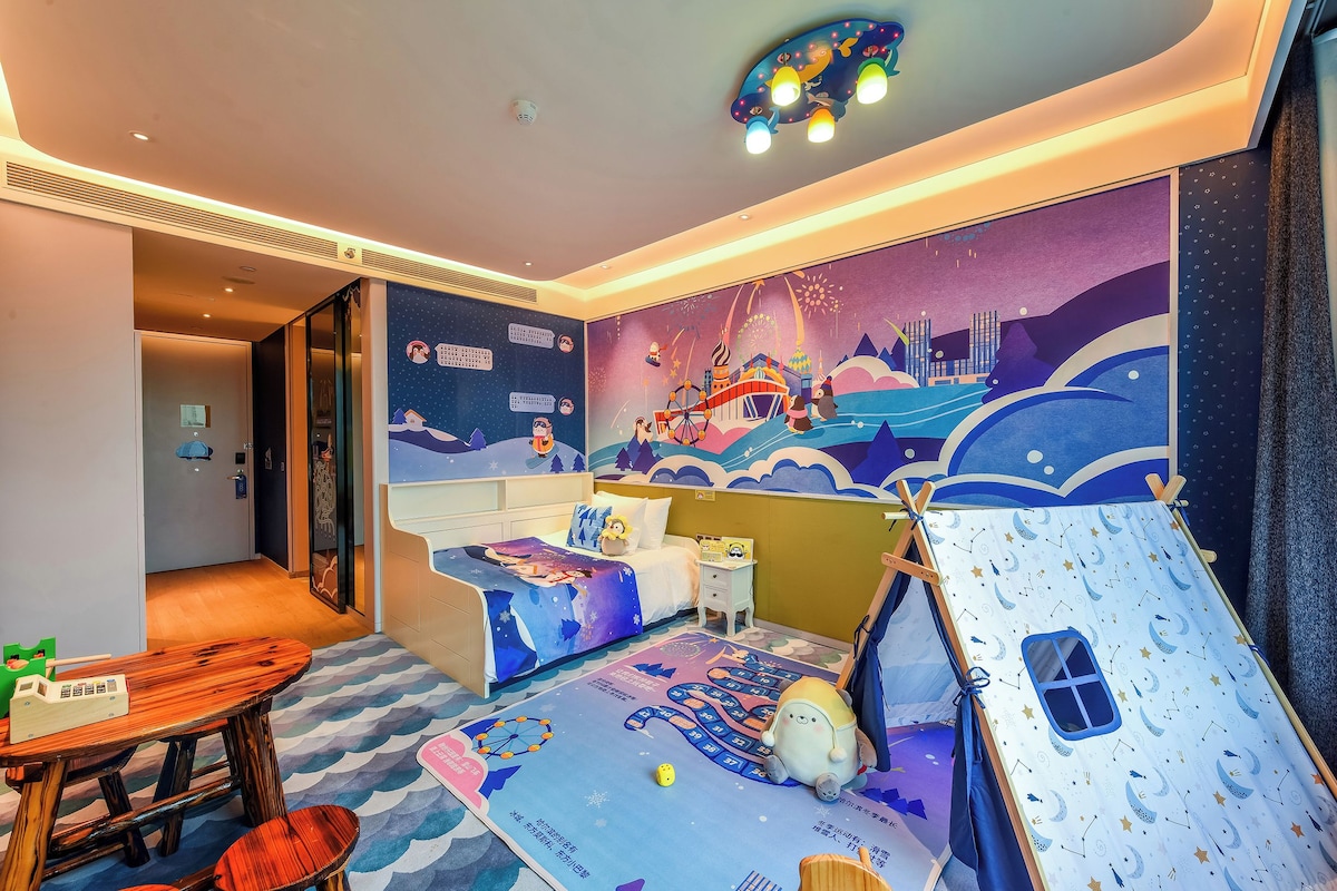 A child's room with a mural, a bed, a small table, and a play tent.