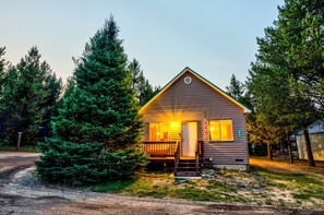 A small cabin with a porch, surrounded by trees. - Rustic Cabin with Firepit for Cozy Summer Night Escapes in Island Park, Idaho (Island Park)