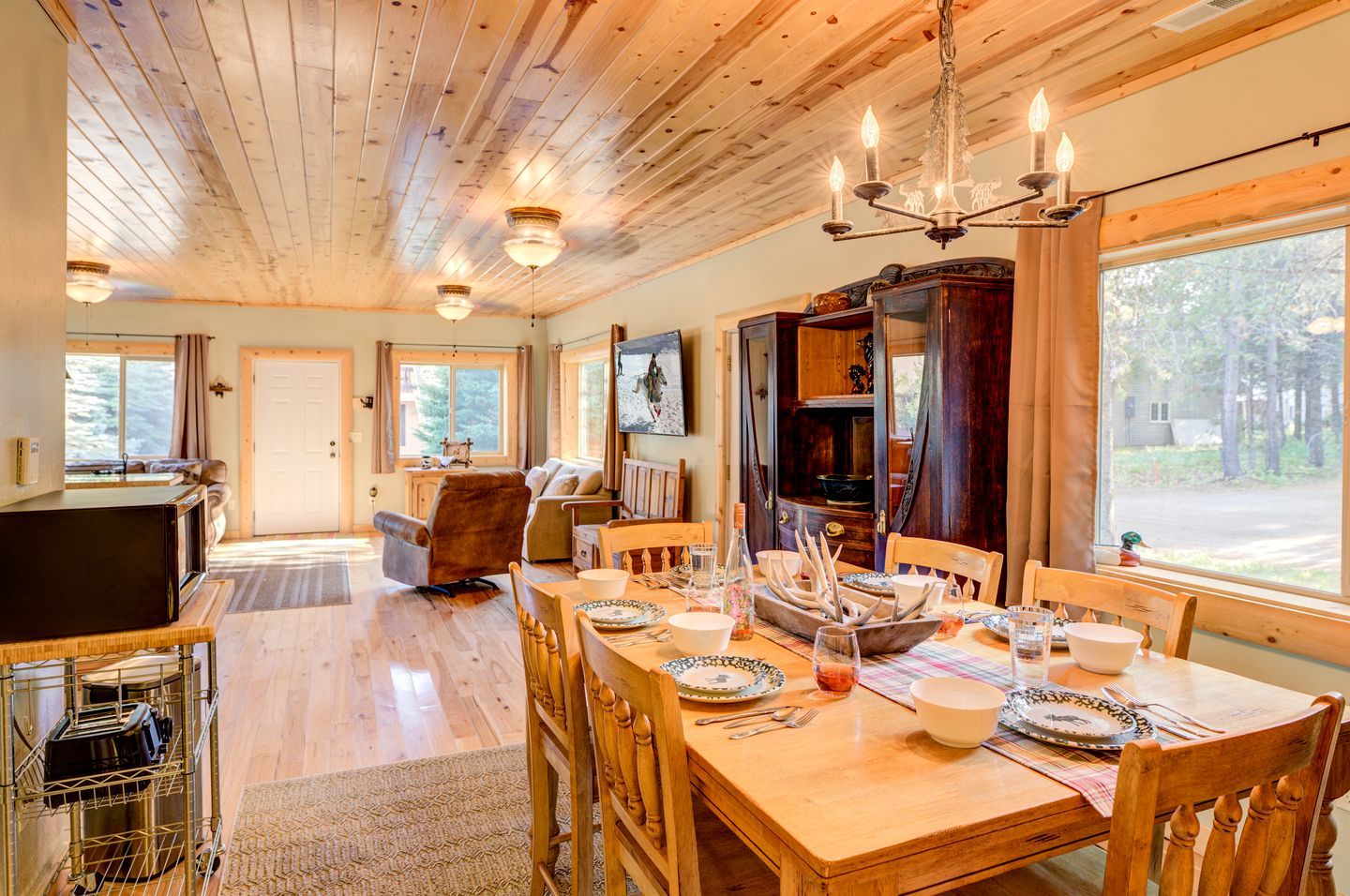 Un intérieur en bois avec une table à manger pour quatre personnes, un téléviseur et une cheminée.