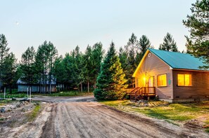 A cabin with a dirt road leading to it, surrounded by trees. - Rustic Cabin with Firepit for Cozy Summer Night Escapes in Island Park, Idaho (Island Park)