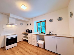 A kitchen with white cabinets, a stove, a window with a view, and decorative plates on the wall.
