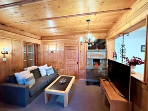 Un accogliente interno in legno con un divano, un tavolino da caffè, un caminetto e un televisore.