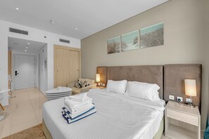 Ein Hotelzimmer mit einem großen Bett, Nachttischen, einem Kleiderschrank und einem durchgegangenen Badezimmereingang.