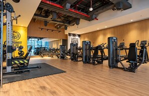 Una palestra con diverse attrezzature per esercizi, pavimento in legno e un muro motivazionale.