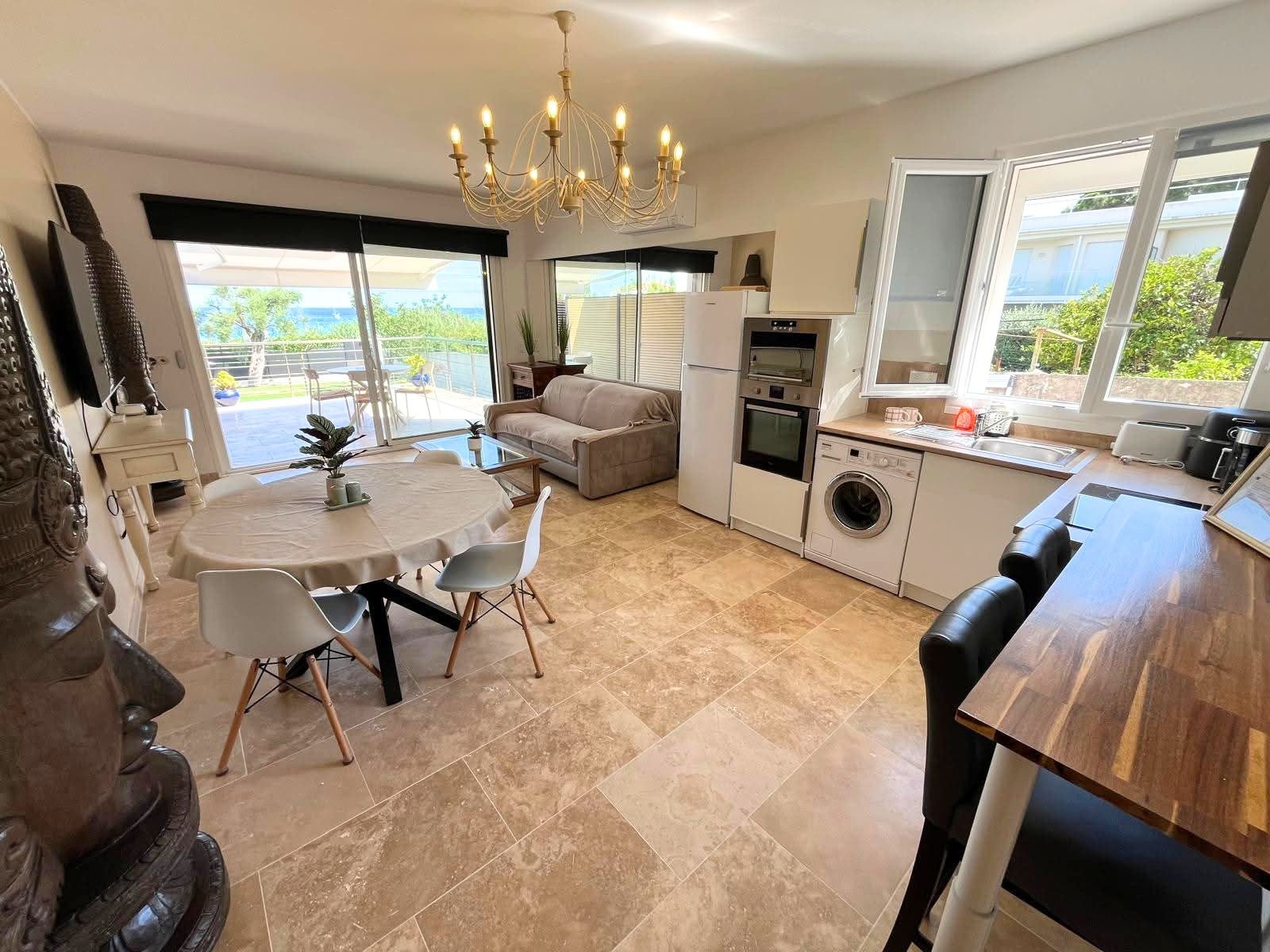 A modern kitchen with a dining area, a washing machine, and a large window.