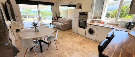 A modern kitchen with a dining area, a washing machine, and a large window.