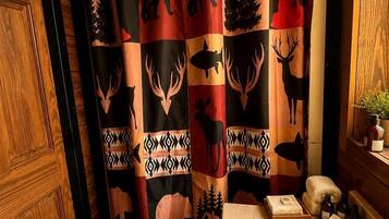 Un baño con cortina de ducha de estampado animal, una puerta de madera y un lavabo con artículos de aseo.
