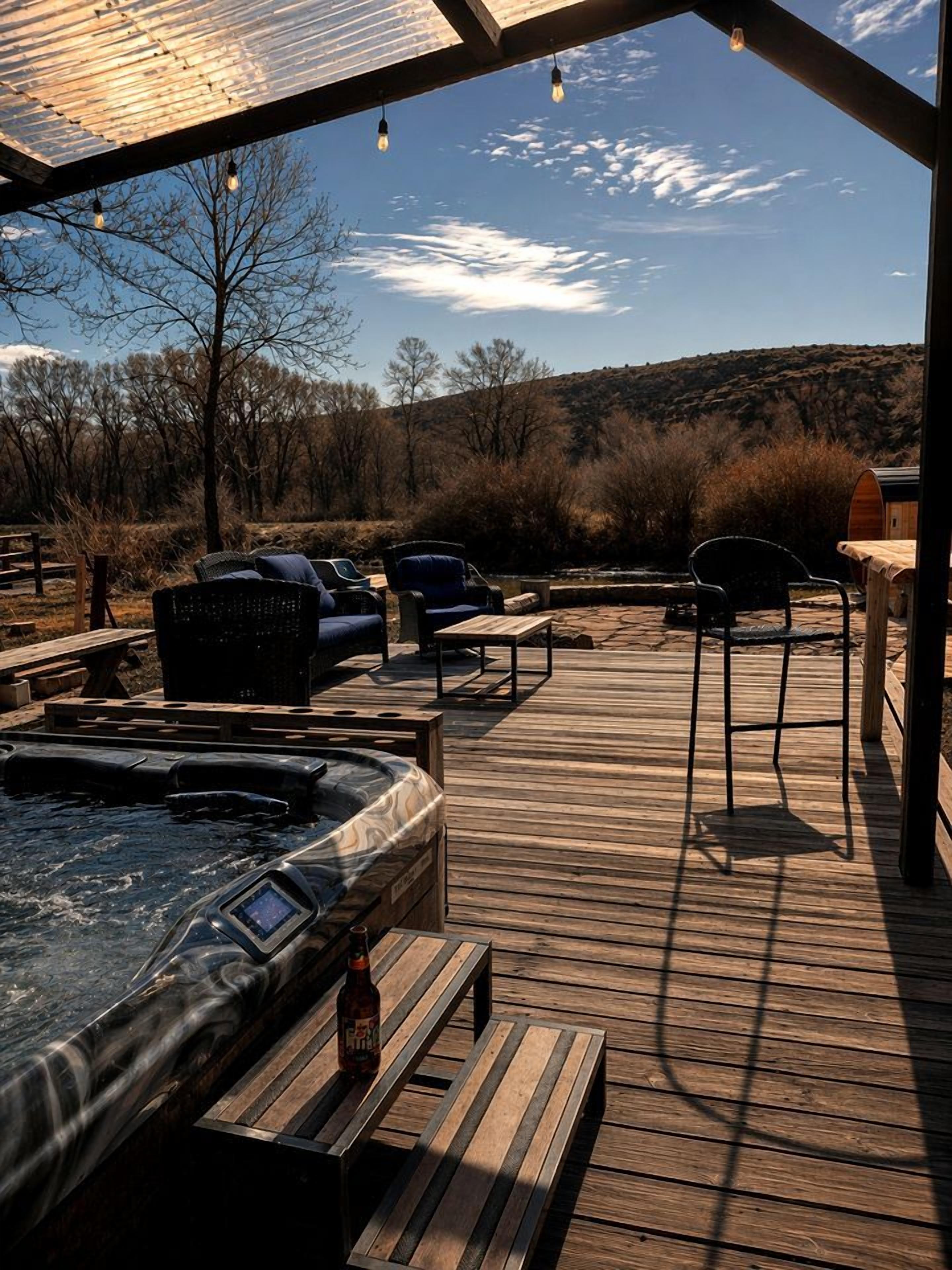 Un espace avec un jacuzzi, des sièges et une terrasse en bois.