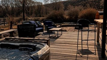 Un espace avec un jacuzzi, des sièges et une terrasse en bois.