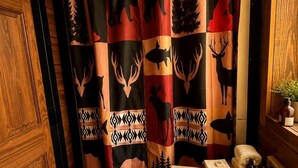 Un bagno con tenda da doccia a fantasia animalier, una porta in legno e un lavabo con articoli da toilette.