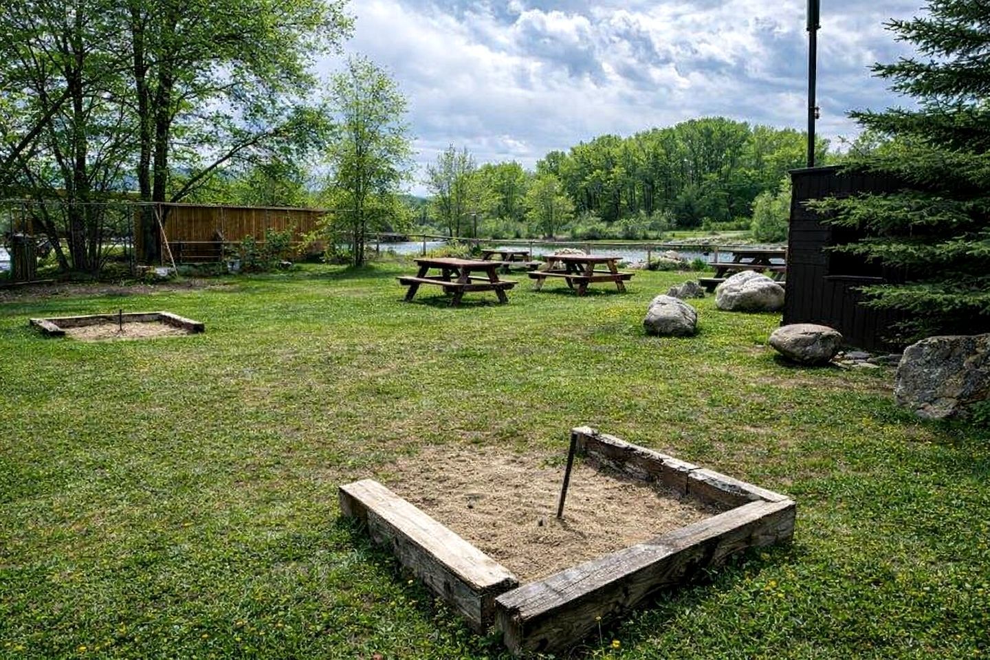 A grassy outdoor area with picnic tables and a small sandbox.