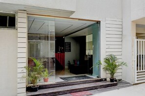 A hotel entrance with a glass door, a welcome sign, and potted plants. - Super Townhouse Marathahalli (Bangalore)