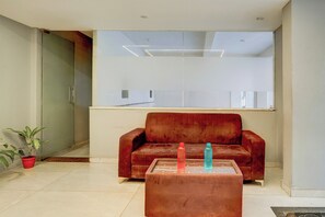A modern living room with a red sofa, a glass coffee table, and a potted plant.