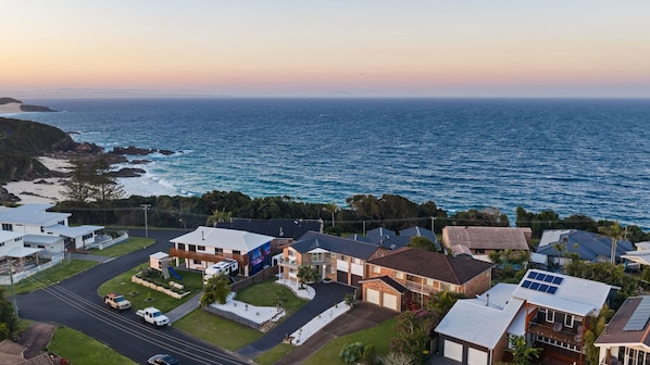 A coastal residential area with houses, a road, and a view of the ocean.