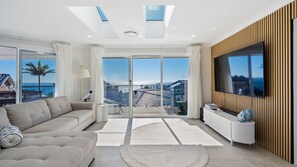 A modern living room with a sofa, a TV, and a view of the city.