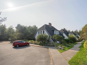 A residential area with houses, a paved driveway, and a red car parked on the street. - OG in the Reimer House (St. Peter-Ording)
