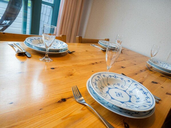 A dining table set with blue and white plates, silverware, and wine glasses. - OG in the Reimer House (St. Peter-Ording)