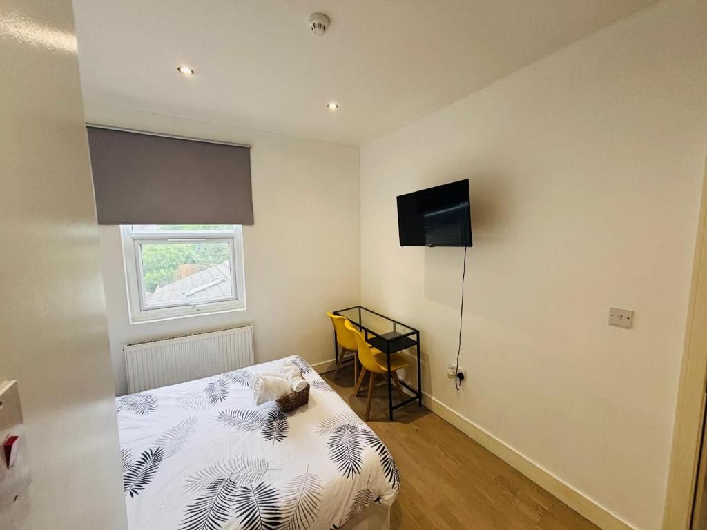 Un dormitorio con una cama, un escritorio, una silla, un televisor y una ventana.
