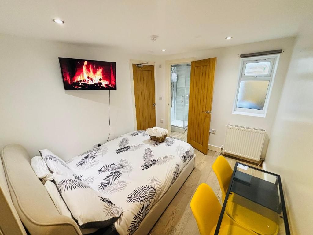 Une chambre à coucher avec un lit, un téléviseur diffusant une image de cheminée, une fenêtre et une porte donnant sur une autre pièce.