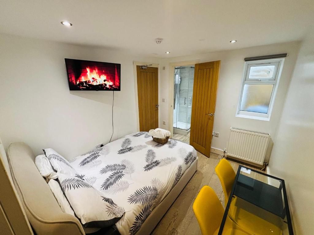 Une chambre à coucher comprenant un lit, un téléviseur fixé au mur, une fenêtre et une porte donnant sur un balcon.