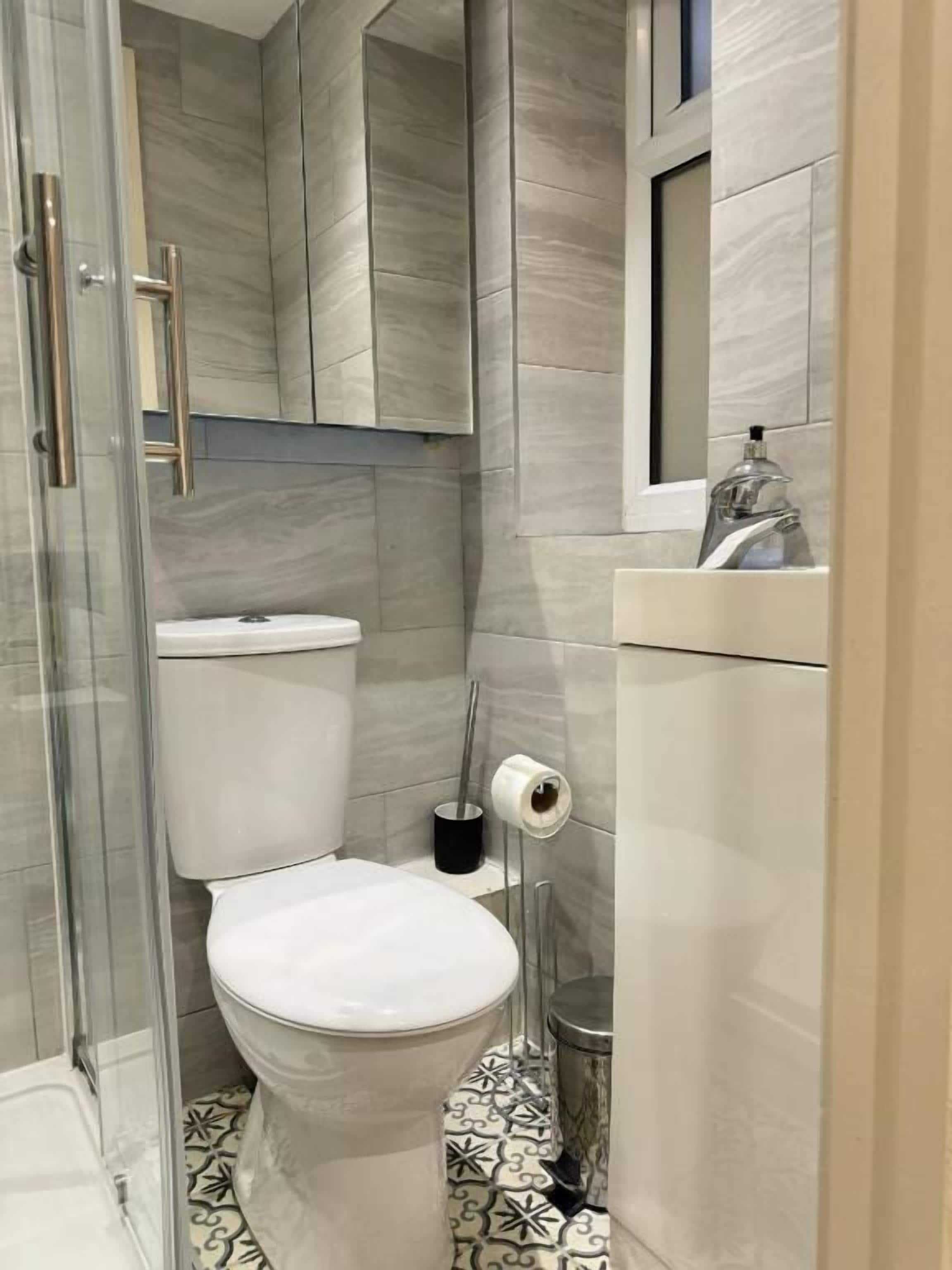 A modern bathroom with a toilet, shower, and sink.