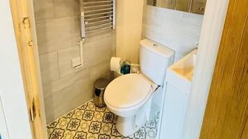 Un baño con inodoro, ducha y piso de baldosas.