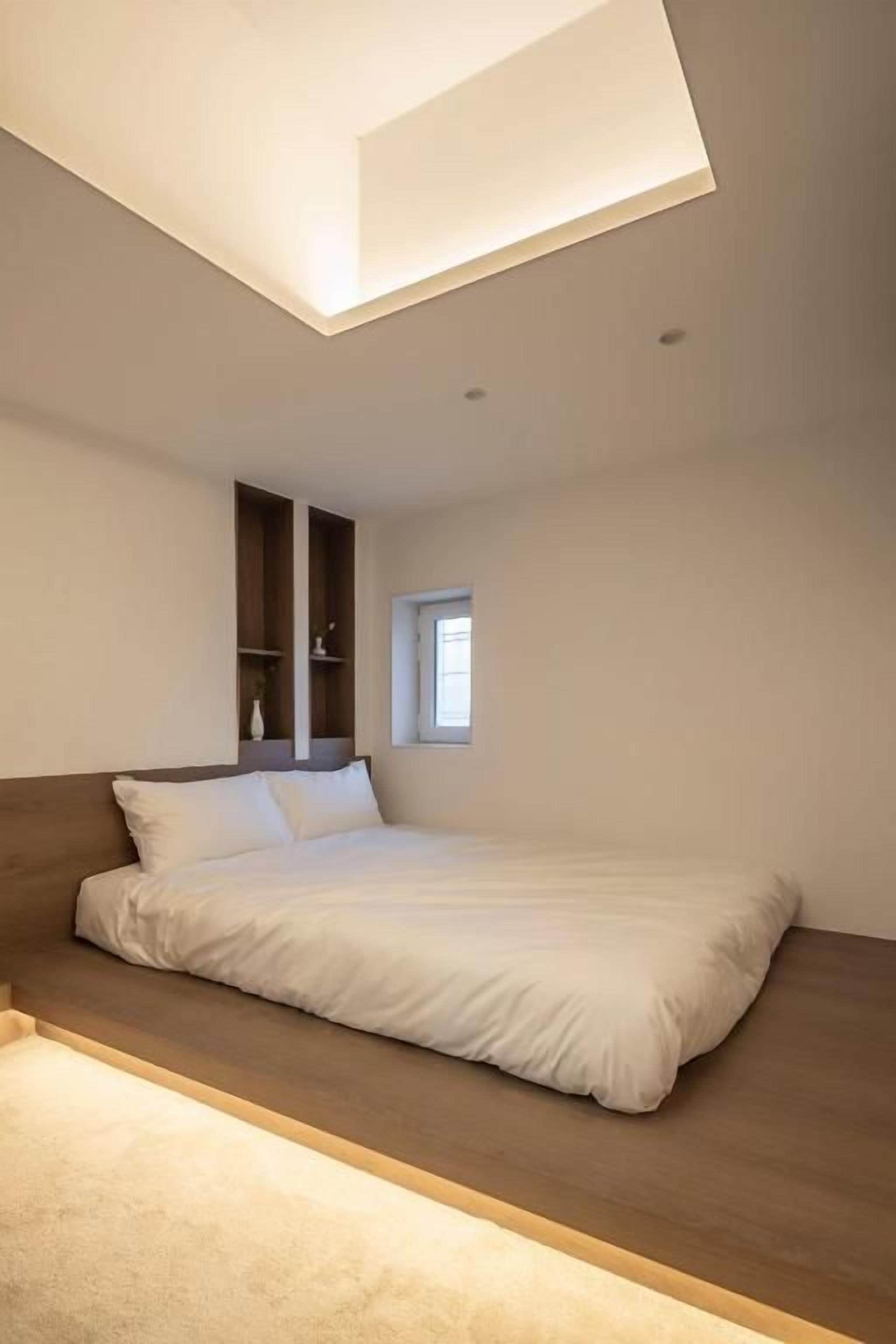 Un dormitorio con cama, estante empotrado y tragaluz.