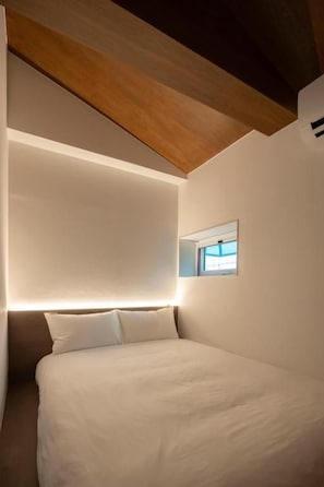 Quarto moderno com cama, mesa de cabeceira e luminária na parede.