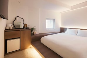 Quarto moderno com cama grande, mesa de cabeceira, espelho e um pequeno armário.