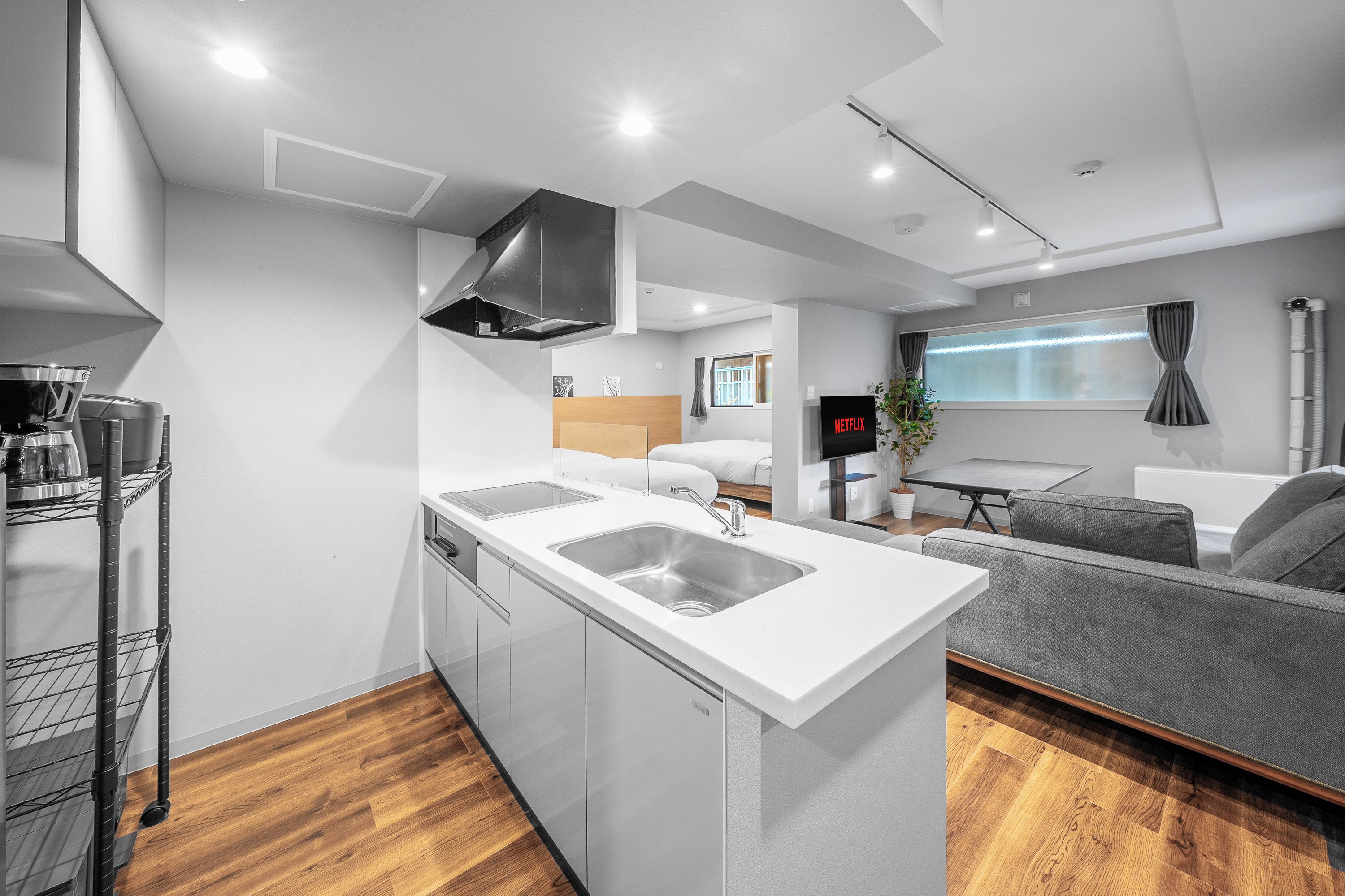A modern kitchen with a central island, a built-in dishwasher, and a grey sofa in the living area.