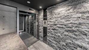 An elevator with a marble wall and a glass door, equipped with a fire alarm and a no-smoking sign. - NOBLE 202 (Sapporo)