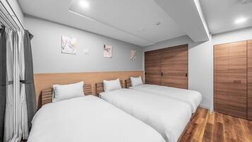 A hotel room with two beds, wooden headboards, a wooden wardrobe, and a ceiling light.