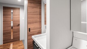 A modern kitchen with a wooden floor, a white countertop, and a built-in oven. - NOBLE 202 (Sapporo)