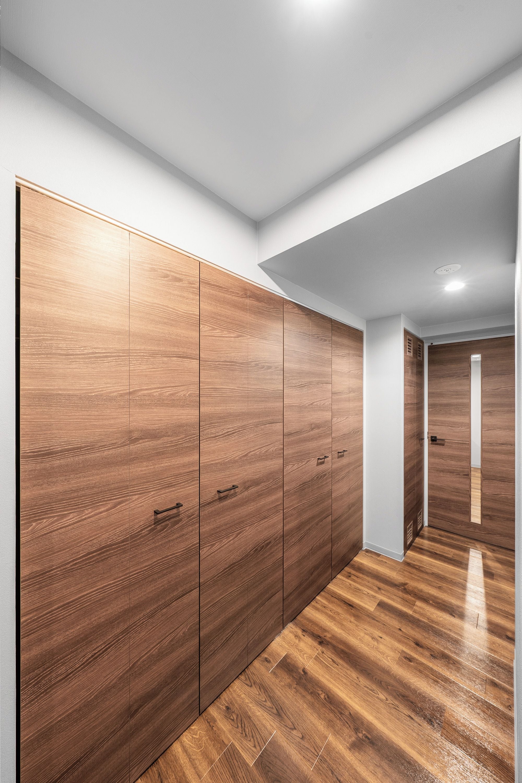 A hallway with wooden flooring and a large wardrobe with multiple doors.