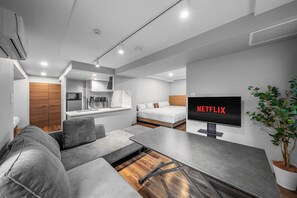 Un espai vital modern i funcional, amb zona de cuina, sofà, taula de dinar i televisió que mostra el logotip de Netflix.