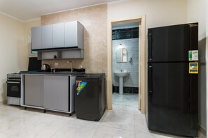 A compact kitchen with a built-in oven, a black refrigerator, and a grey cabinet. - Peaks - El Nessim-1BR-Pool View R106 (Hurghada)