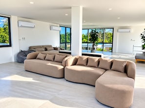 A modern living room with a sectional sofa, a bean bag, and a view of a swimming pool.