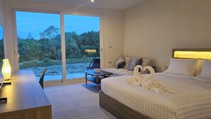 A hotel room with a bed, a desk, a chair, and a view of a natural landscape through a sliding door. - Mangrove Resort Phuket Airport (Thalang)