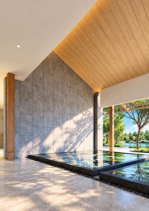 Ein modernes Interieur mit Pool, Steinwänden und Holzboden.