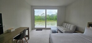 A modern bedroom with a bed, a sofa, a desk, and a television.