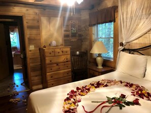 A wooden cabin bedroom with a bed, dresser, and a chair. - Rustic Cabin Rental in the Forest near Charleston, West Virginia (Hico)