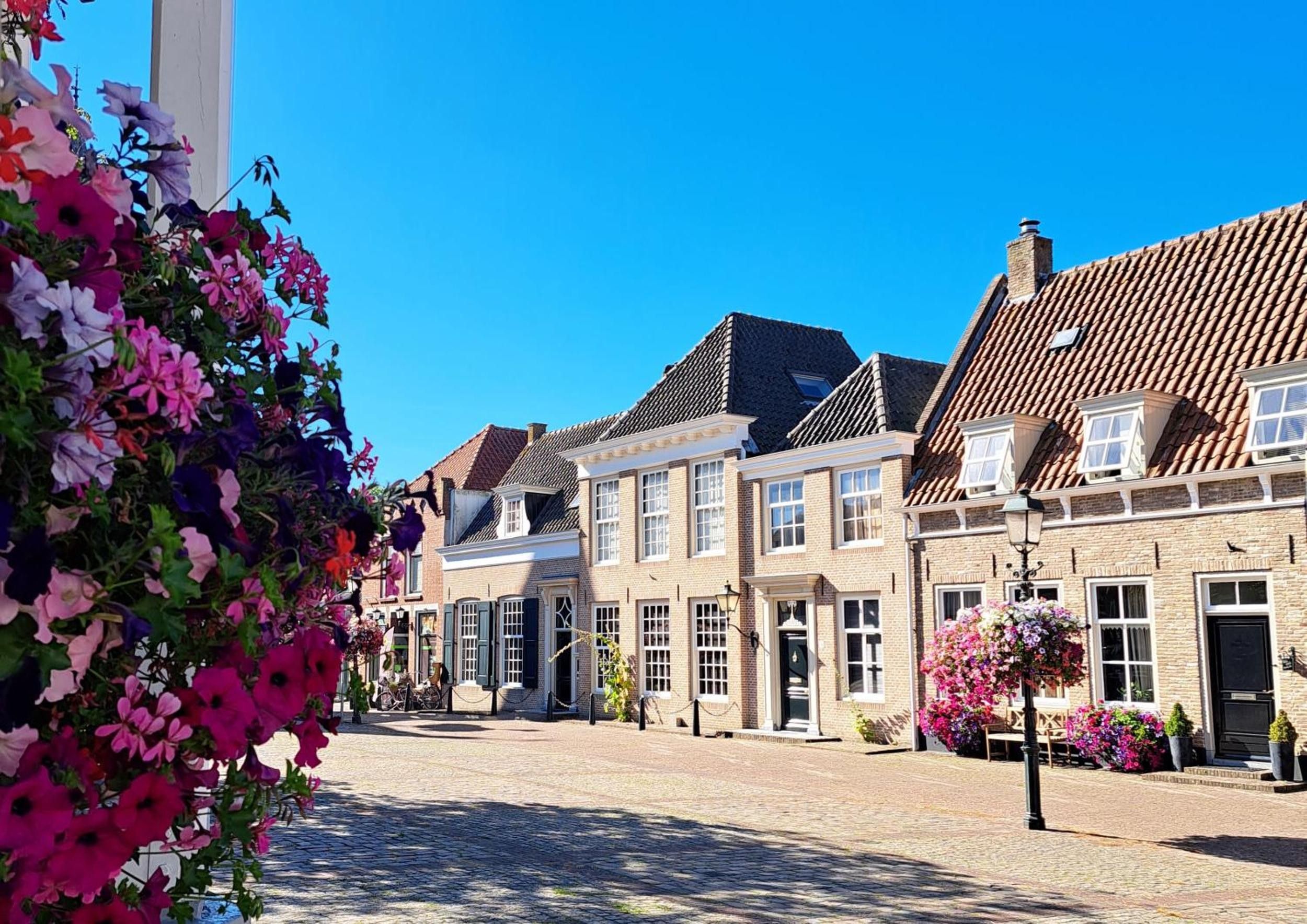 A traditional European street with historic buildings, cobblestone pavement, and flower arrangements.