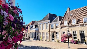 Eine typische europäische Straße mit historischen Gebäuden, Kopfsteinpflaster und Blumenarrangements.