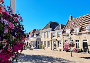Een typische Europese straat met historische gebouwen, kinderaardewerktegels en bloemen decoraties.