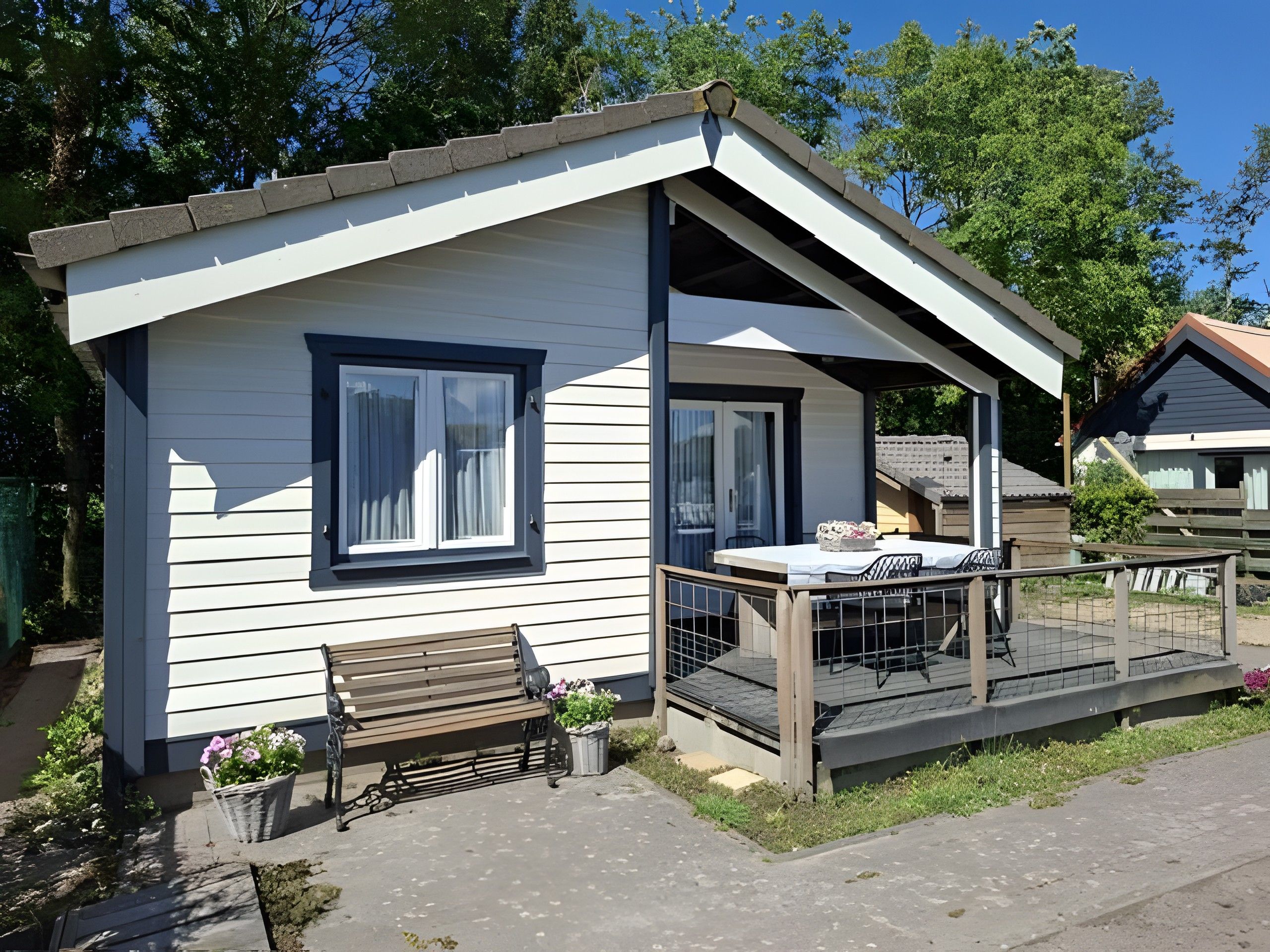 A small, single-story building with a porch and a bench.