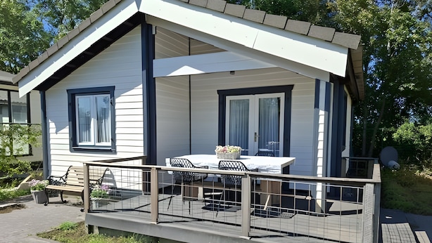Ein Bungalow mit Balkon, einem Esstisch mit Stühlen und einem kleinen Garten.