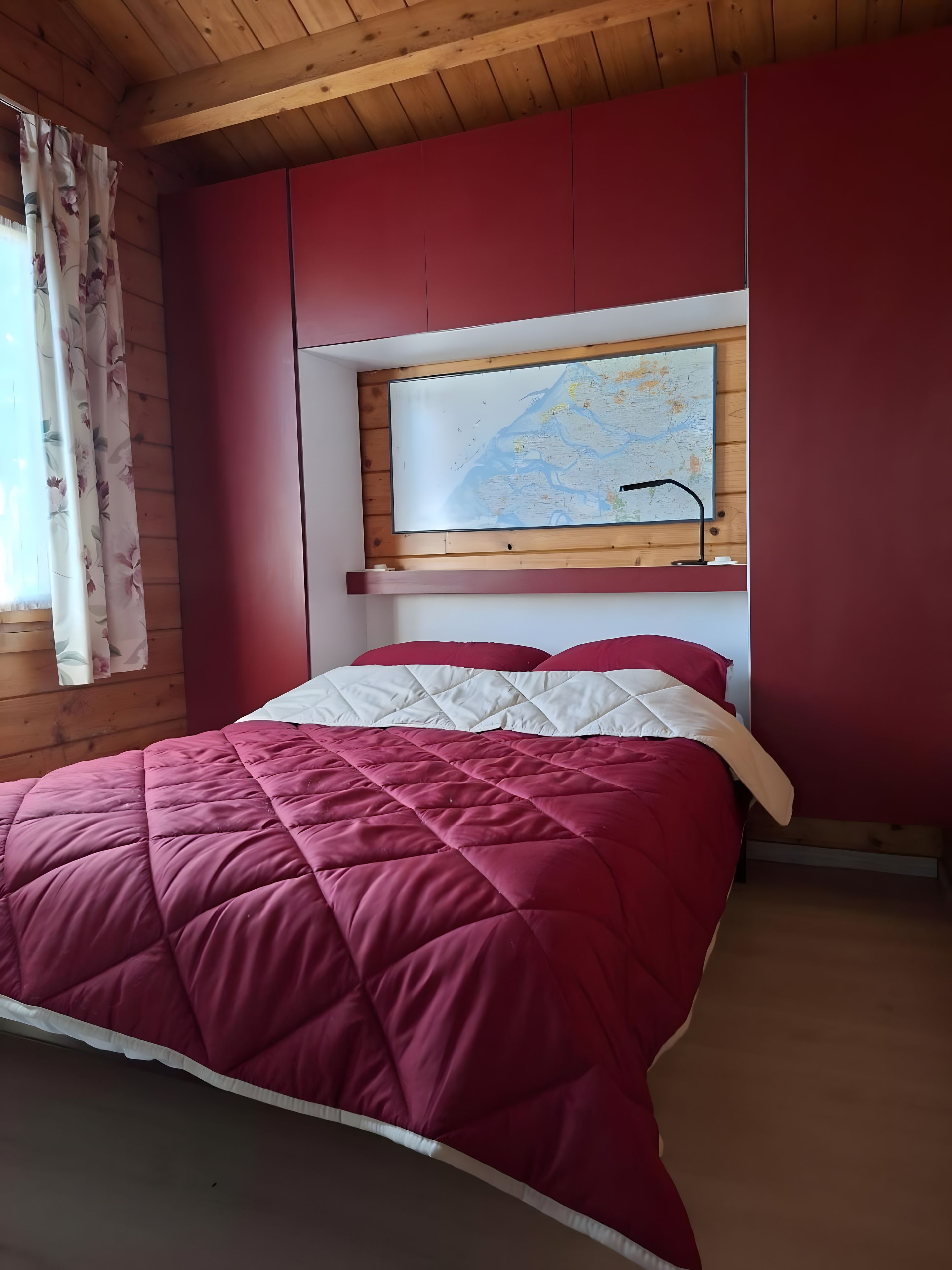 A room with a bed, a map on the wall, and wooden paneling.
