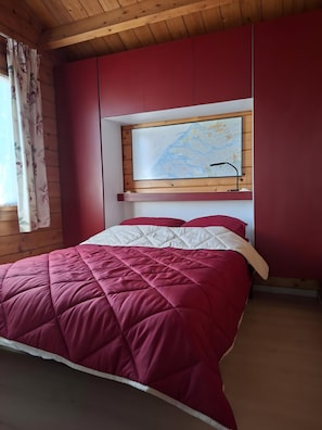 Een kamer met een bed, een kaart aan de muur en houten lambrisering.