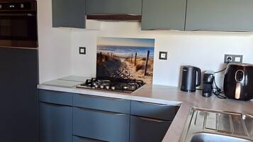 Een moderne keuken met grijze kastjes, een roestvrijstalen spoelbak en een gasfornuis.
